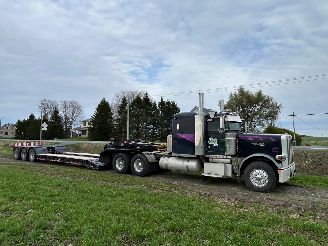 Camion Peterbilt et fardier de Les MultiBois Gilbert en bordure d'une route rurale