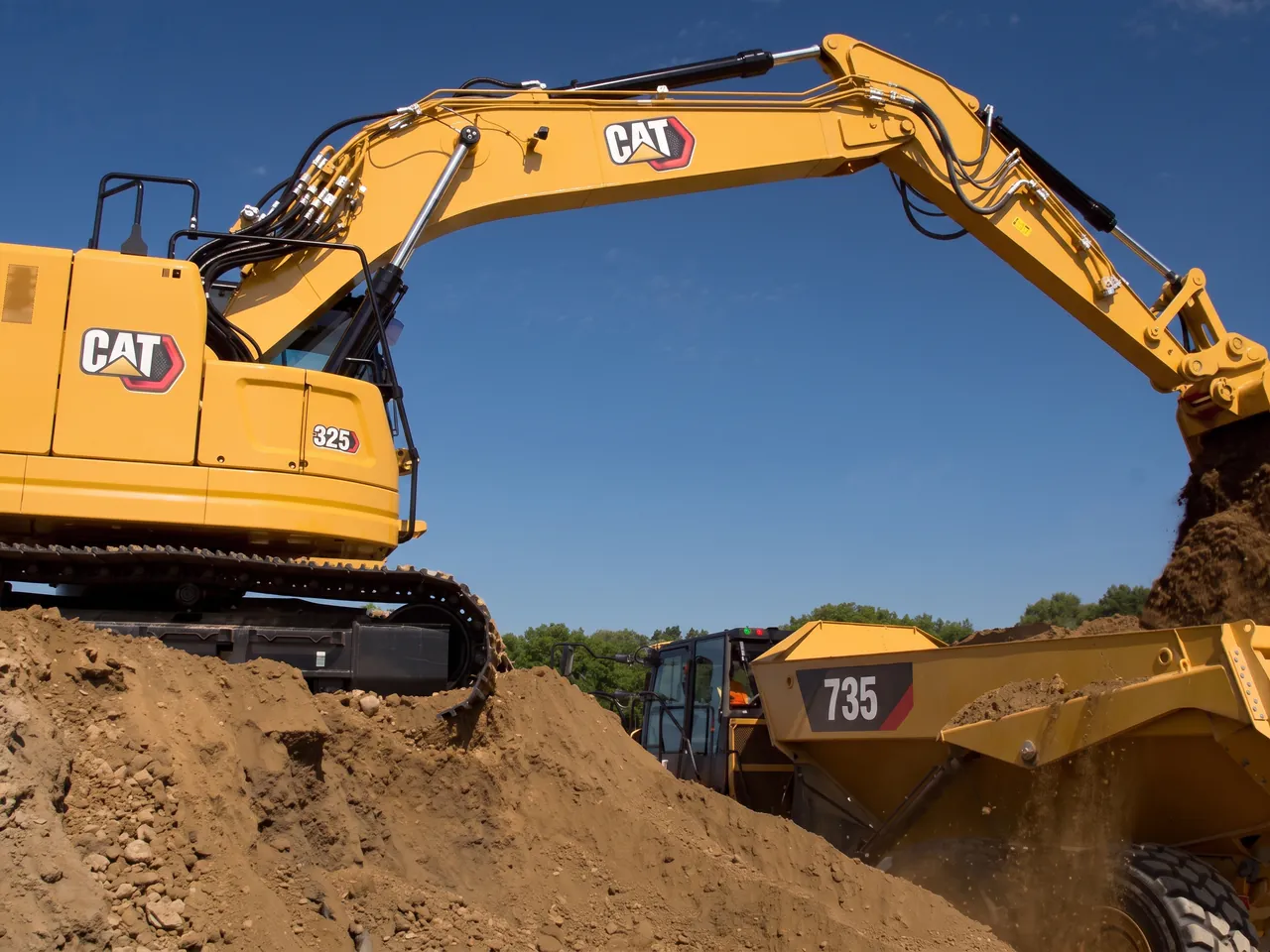 Excavatrice Caterpillar 325 chargeant un tombereau articulé Caterpillar 735